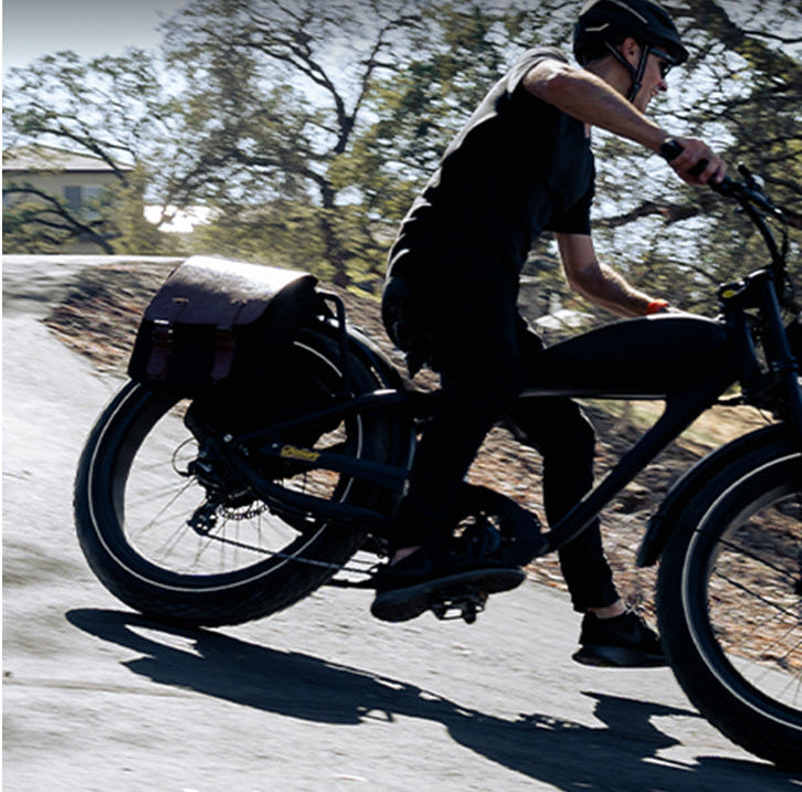 Rider in motion on a ROOTS RIDER Cheetah 2 electric bike with leather saddle bags