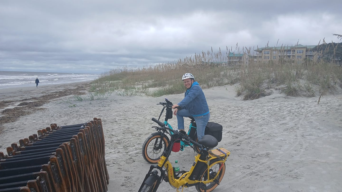 Rider on an electric bike along a grey, overcast shoreline