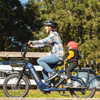 Parent riding a Roots Rider Flux cargo electric bike with a child seated on the rear deck