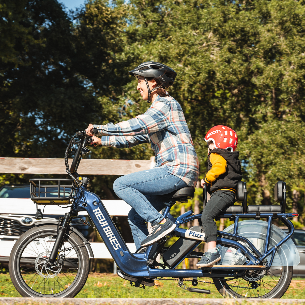 Parent riding a Roots Rider Flux cargo electric bike with a child seated on the rear deck